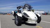 A 2013 Can-Am Spyder, a three-wheeled motorcycle with a sleek white body, large front headlights, and a sporty design, prominently featuring a side storage compartment