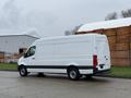 A 2019 Mercedes-Benz Sprinter van with a white exterior and dark accents parked on a street, showing its side profile and cargo area