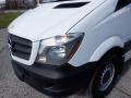 A 2016 Mercedes-Benz Sprinter van with a white body and black front bumper showcasing its headlights and grill design
