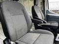 Two gray fabric seats in a 2018 Ford Transit van with adjustable armrests and seatbacks in an empty interior space