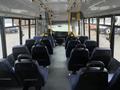 Interior view of a 2017 Chevrolet Express showing rows of blue fabric seats facing forward with a driver area at the front and open space in the middle