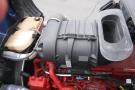 A detailed view of the engine compartment of a 2015 Kenworth T660 featuring a black air intake and various engine components in red and gray colors