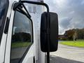 A 2016 Isuzu NPR truck with a black side mirror visible in the foreground