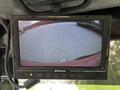 A screen displaying a rearview camera feed from a 2012 Toro Groundsmaster showing a paved surface with no obstacles in view