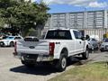 A white 2020 Ford F-350 Super Duty pickup truck with a 4x4 badge viewed from the rear showing its bed and chrome exhaust tips