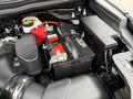 A close-up view of the engine compartment of a 2019 Ford Explorer showing the battery with red connectors and a black housing unit