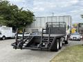 A black 1998 Freightliner FL80 with a flatbed and dual rear wheels parked in an industrial area
