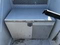 A silver diamond plate toolbox with a latch sits inside a vehicle compartment