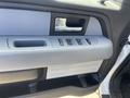Interior door panel of a 2012 Ford F-150 featuring a silver handle and control buttons for windows