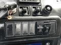 Control panel of a 2012 Autocar Xpert with various switches and knobs including cruise control buttons and a key ignition