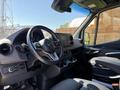Interior view of a 2023 Mercedes-Benz Sprinter showing the steering wheel dashboard and front seats with modern controls and touchscreen display