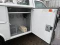 A white 2006 Ford F-450 with an open service body displaying interior storage hooks and equipment mounted inside the compartment