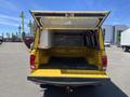 A yellow 2015 RAM 1500 pickup truck with the tailgate down and the canopy raised exposing the empty truck bed and interior frame structure