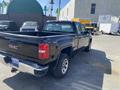 A black 2014 GMC Sierra 1500 pickup truck with a visible bed and rear view, showcasing its distinctive taillights and GMC logo on the tailgate