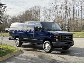 A blue 2011 Ford Econoline van parked at an angle with sliding side doors and a tall roof design