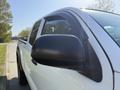 A 2015 Toyota Tacoma with a white exterior and black side mirror visible in the foreground