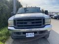 A 2002 Ford F-550 truck with a black grille and orange roof lights parked on a road