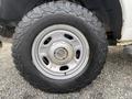 A close-up of a silver wheel on a 2015 Ford F-250 SD with rugged black off-road tires and visible tread patterns