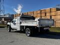 A 2008 Ford F-450 Super Duty truck with a flatbed and metal sides parked on a street