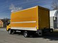 A 2017 Hino 155 truck with a bright yellow box-shaped cargo area and white stripes on the sides parked on a road