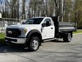 A 2018 Ford F-550 truck with a white cab and black flatbed parked on a concrete surface