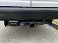 The rear hitch receiver of a 2011 Ford Econoline van is visible showing a black tow hitch and mounting area