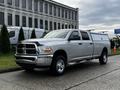 A silver 2012 RAM 3500 pickup truck with a long bed and cab cover parked on a street