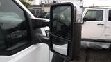 A close-up view of the side mirror of a white 2011 Ford F-550 with droplets of water on its surface