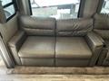 A brown leather sofa designed for a 2021 Grand Design Recreational 311BHS with a simple and modern style