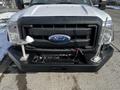 Front view of a white 2011 Ford F-450 Super Duty with a missing grill and metal mounts on the bumper