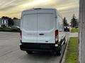 A 2017 Ford Transit van with a white exterior parked on a pavement showing its rear end and tail lights