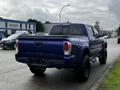 A blue 2022 Toyota Tacoma with a black bed cover and rugged tires displayed from the rear angle