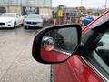 A close-up of the side mirror of a red 2016 Mitsubishi Outlander with raindrops on the surface