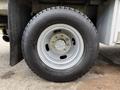 A close-up of a tire from a 2015 Ford F-350 SD showcasing a silver alloy wheel and a rugged tread pattern