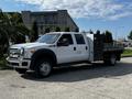 A 2016 Ford F-550 with a flatbed and tool storage compartment parked on a driveway