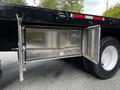A 2011 International 4400 truck with an open metal storage compartment featuring a diamond plate surface and dual doors on the side of the vehicle