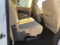 The interior of a 2014 Ford F-350 SD showing the rear seating area with bench seats in beige upholstery and seat belts