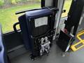 A folded blue bus seat with a manual and a phone resting on top in a transit vehicle
