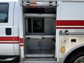 A 2009 Ford F-550 fire truck with an open compartment showing empty storage shelves and a metal baseplate inside
