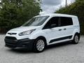 A white 2016 Ford Transit Connect van with black accents and alloy wheels is parked at an angle showcasing its front and side view