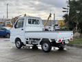 A 2009 Suzuki Carry white mini truck with an open flatbed and a compact design parked in a lot