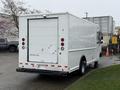 A white 2012 Ford Econoline van with a large rear cargo door and red brake lights is parked in a lot