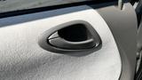 Close-up of the interior door handle of a 2006 Honda Fit with a textured finish and a curved design