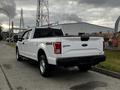 A white 2016 Ford F-150 parked on a street showing the rear view with the 4x4 badge visible on the tailgate