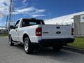 A white 2010 Ford Ranger pickup truck viewed from the rear with shiny alloy wheels and the model name visible on the tailgate
