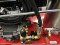 Close-up of the pressure washer's pump and hoses showing a black and gold pressure control valve and a red shut-off switch attached to the Magnum 4000 model