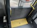 A yellow and black wheelchair ramp with a metal mesh barrier on a bus interior