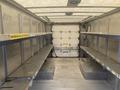 The interior of a 2012 Ford Econoline van features metal shelving units along the sides and an open space in the center with a loading area at the back