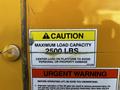 A caution sign on a yellow Hino 155 truck displaying maximum load capacity of 2500 lbs and warnings about proper usage to avoid personal or property damage