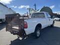 A white 2013 Ford F-250 SD pickup truck with a metal flatbed and rear gate positioned at an angle
